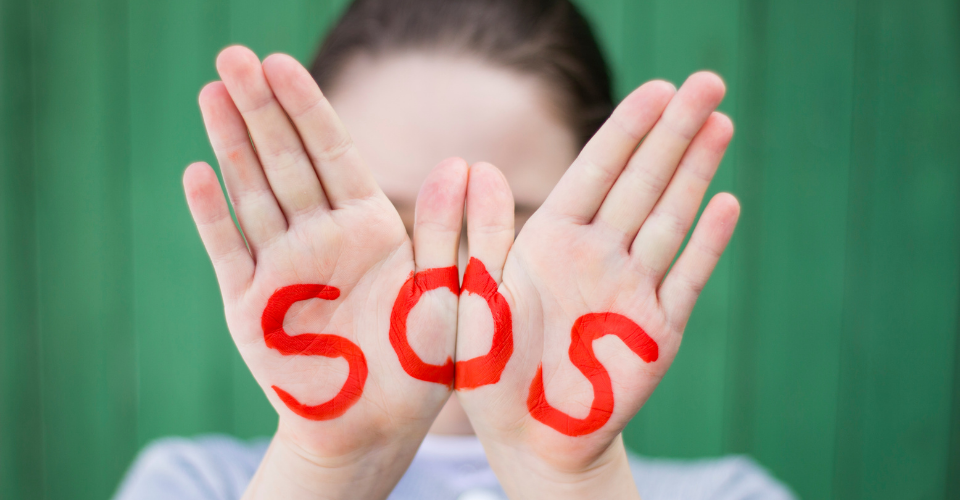 Girls with SOS written on hands